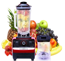 Red blender with pitcher filled with fruit, surrounded by pineapple, lemon, apple, grapes, berries and banana; a small personal blender sits beside.