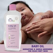 Bottle of baby oil with a pink cap in the foreground; a baby lies in the background, suggesting gentle moisturization for infants.