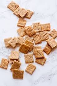 Several square crackers scattered on a white marble surface.