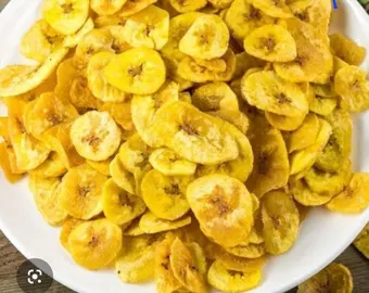 White bowl filled with fried banana chips, golden yellow with some brown specks.