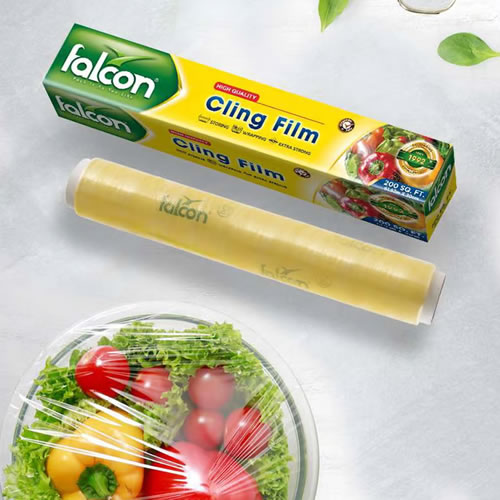 Falcon Cling Film 1500g 2 - Imavug Falcon cling film roll with yellow box labeled Cling Film, shown with a salad nearby for food wrapping.