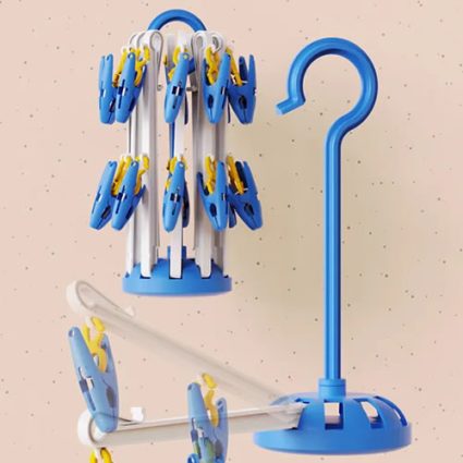 Blue and yellow clothespins clipped to a compact vertical clothes-drying rack beside a blue curved hanger stand on a speckled wall.