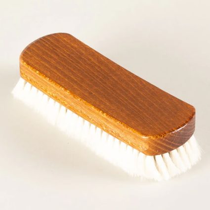 Wooden-handled hairbrush with white bristles for grooming hair (close-up).