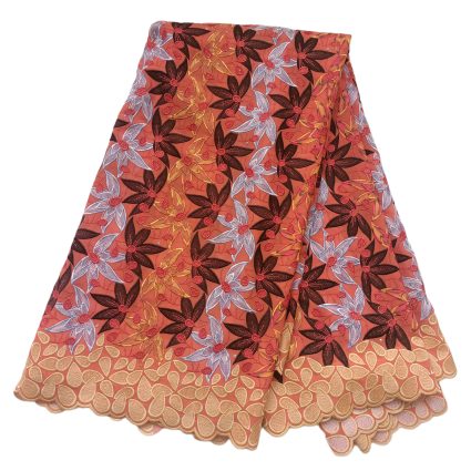 Coral fabric covered in multicolored embroidered flowers with a scalloped beige border, suggesting a decorative skirt or dress trim.