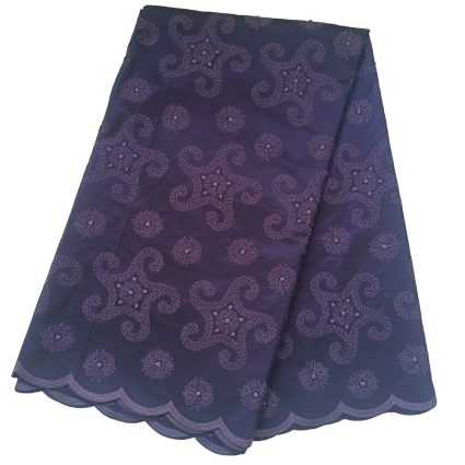 Purple-blue fabric with intricate embroidered swirl patterns and a scalloped hem edge lauding the decorative textile.