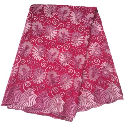 Pink lace fabric with a white floral and swirl pattern, layered with a scalloped edge showing intricate decorative borders.