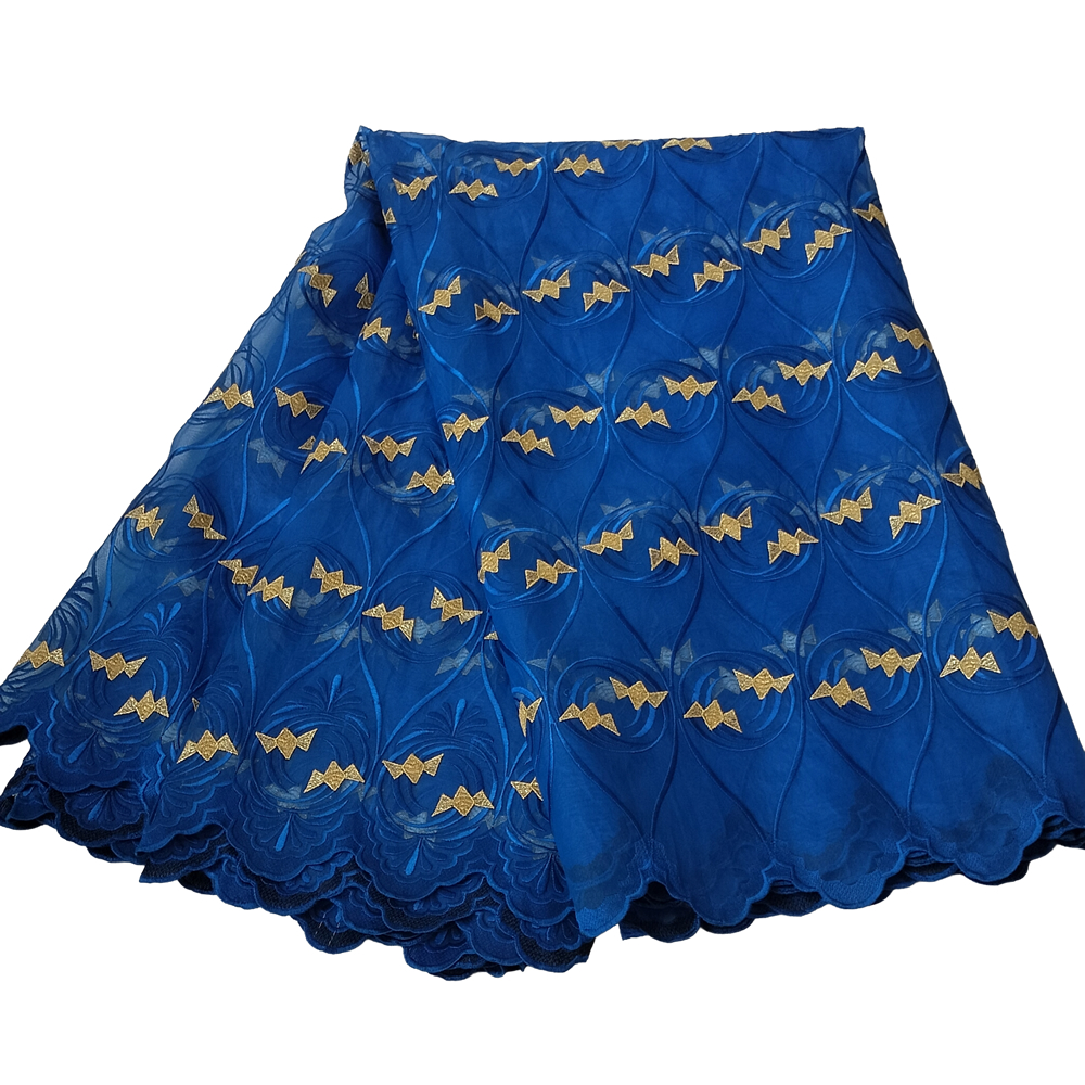 Premium Royal Blue Swiss Voile Lace Fabric with Geometric Gold Embroidery 5 Yards - Imavug Blue lace fabric with gold bow motifs and scalloped edges, layered for a dress.