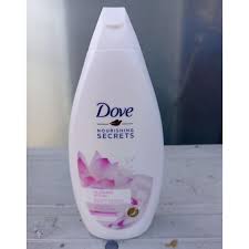 Dove Nourishing Secrets body wash bottle, white with pink floral label, standing on a light wooden surface.