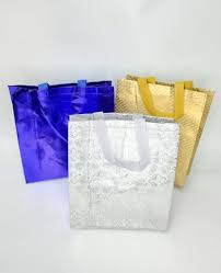 Three decorative gift bags in purple, white, and gold with ribbon handles arranged together.