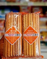 Two clear plastic bags of snack sticks with orange labels on a grocery store shelf area.